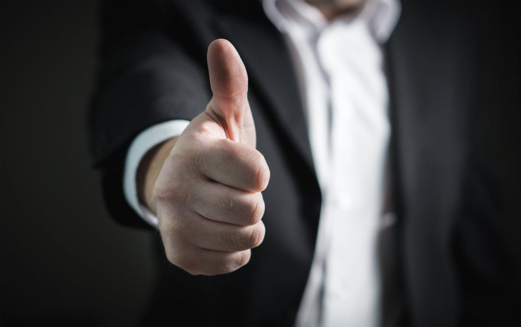 A close-up of a mans thumbs up gesture, symbolizing success and agreement.